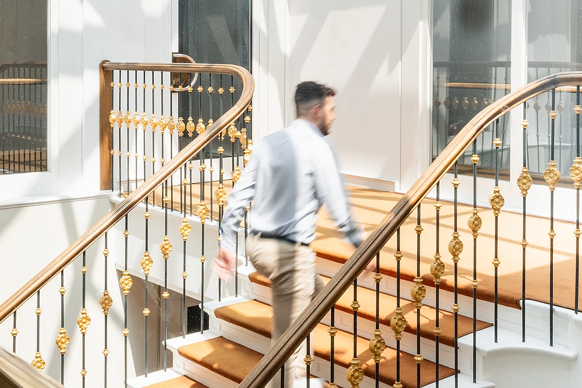 Historic staircase with gilded balustrade and carpet runner in the Colonnaden building in Hamburg