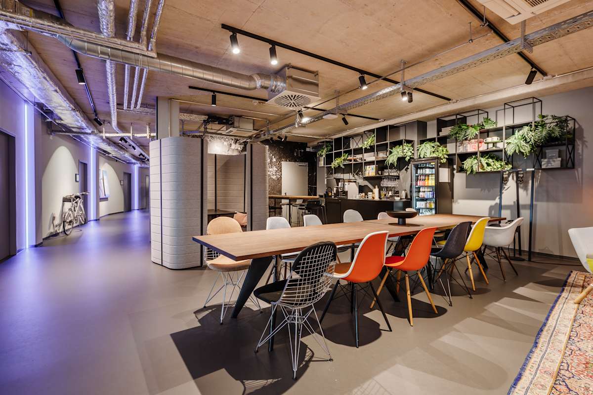 Kreativfläche mit langen Tischen und farbigen Stühlen, Design Offices Nürnberg Hauptbahnhof