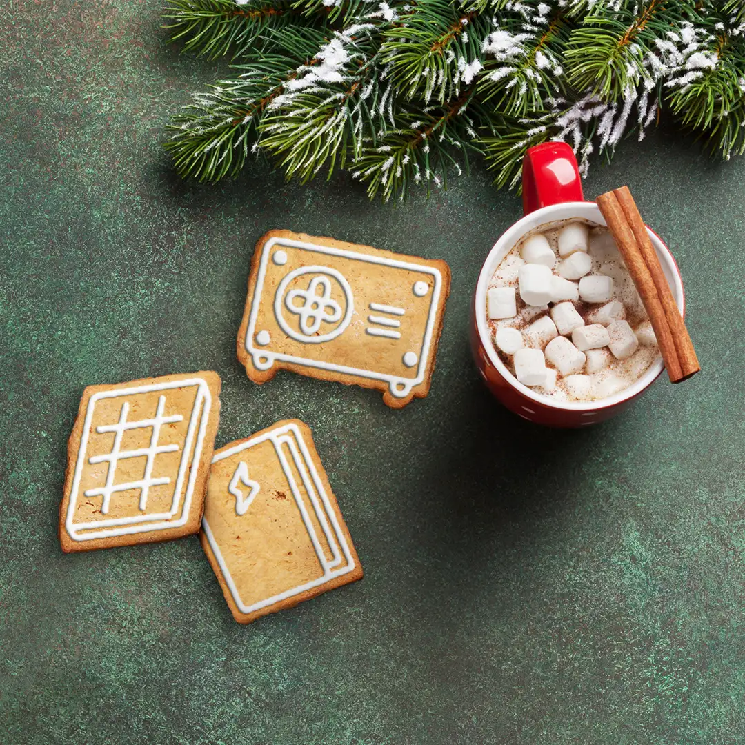 A warm cup of hot chocolate, with three cookes, each decorated with the shape of a heat pump, solar panel and battery in piped icing cream