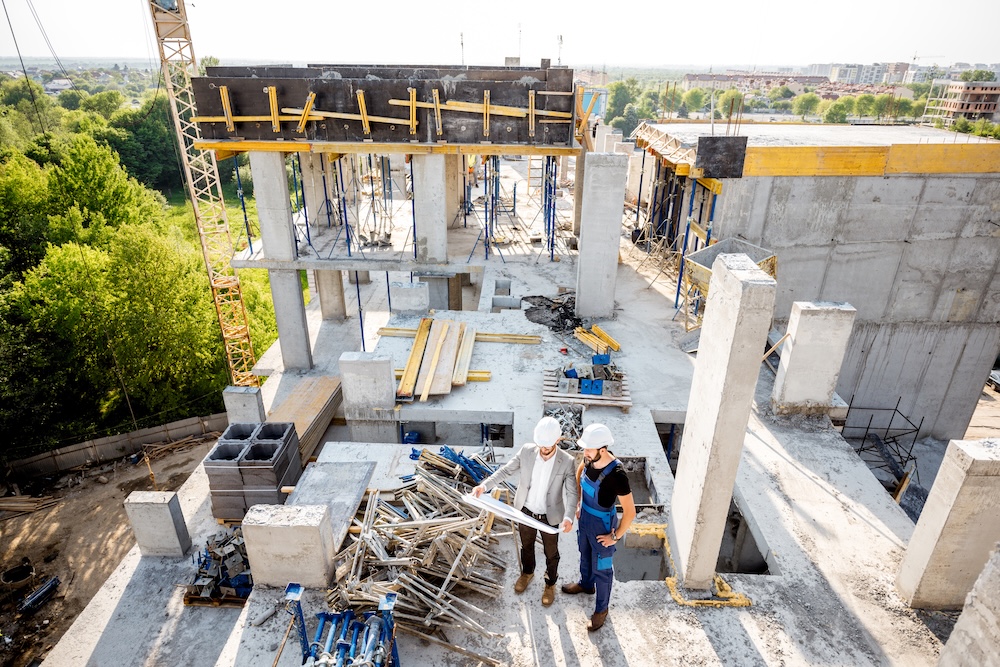 two men on building site looking at blueprints