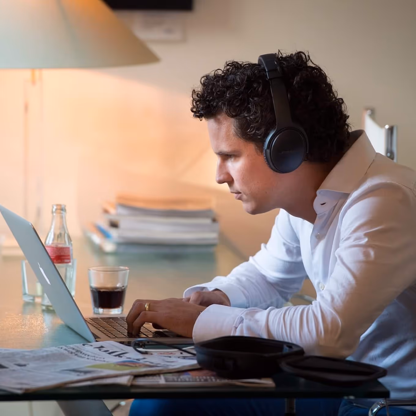 Een man  met koptelefoon kijkt geconcentreerd naar een laptop.