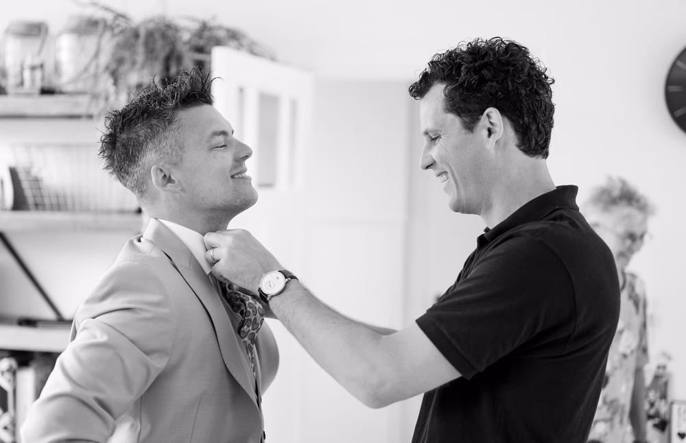 Een man versteld de stropdas van een andere man in pak.