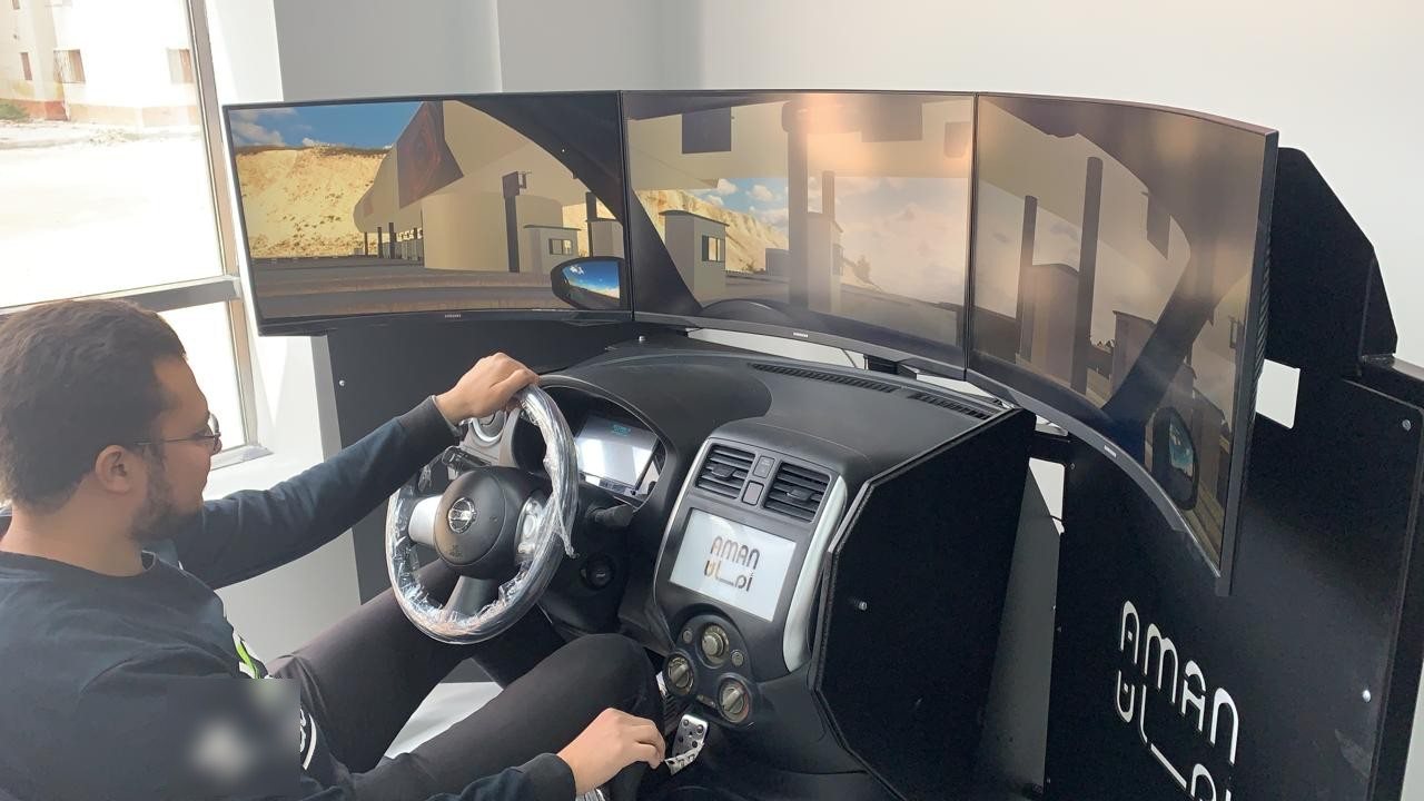 Driver at the wheel of the Aman driving simulator built by Genesis, with three curved screens