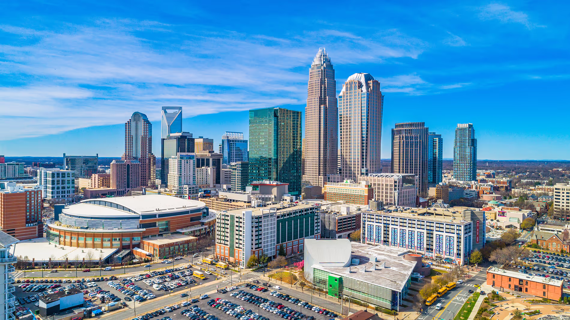 Aerial view of a city skyline with tall buildings and a sports arena on a clear day.