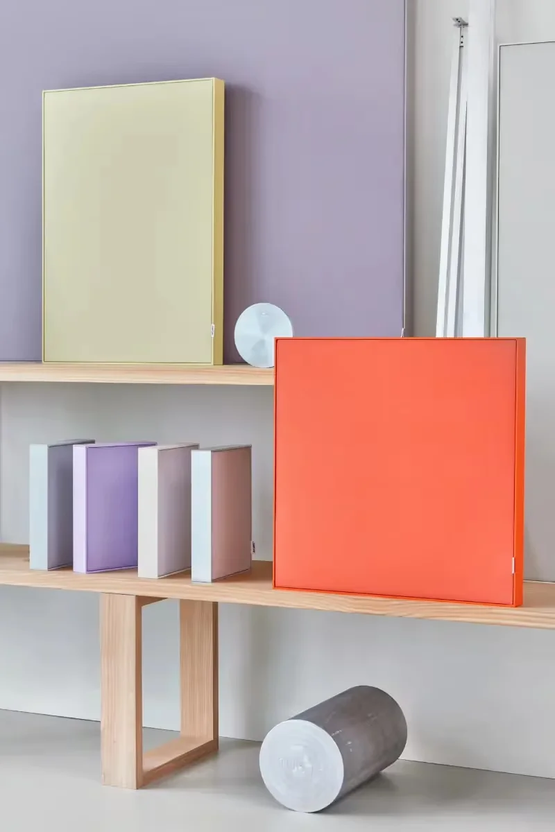 Handen die tonen hoe het canvas van een Akuart SS50 akoestisch wandpaneel eenvoudig wordt verwisseld zonder het frame van de muur te halen