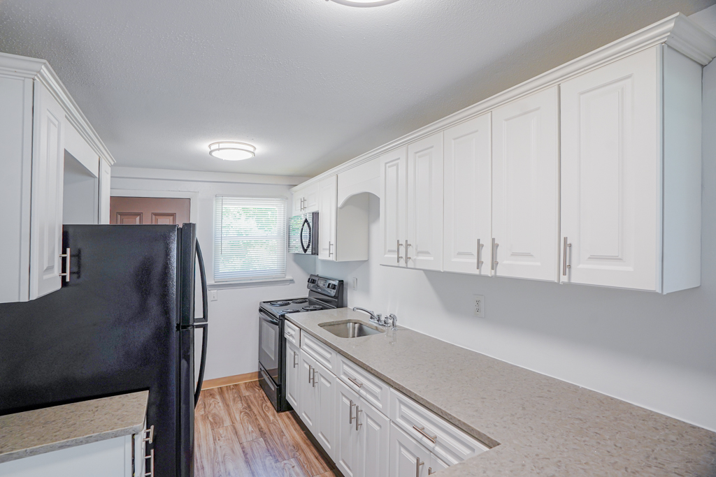 Modern kitchen at The Den in Willington, CT, featuring a black appliances and white cabinetry 