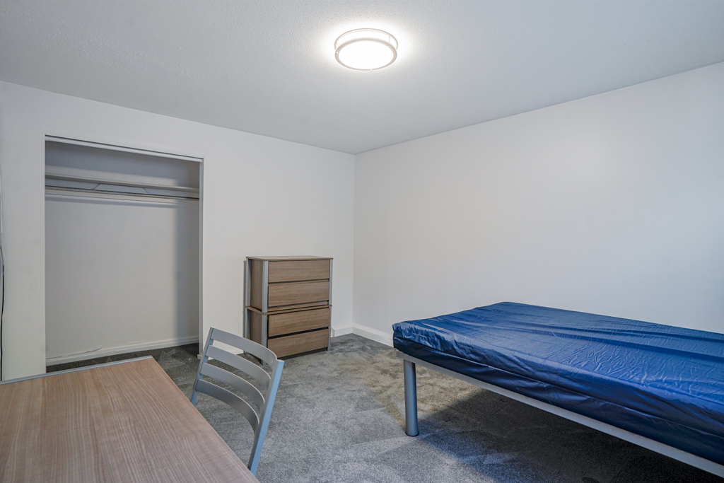 Cozy bedroom at The Den in Willington, CT, styled with a metal bed frame, desk area, and wardrobe