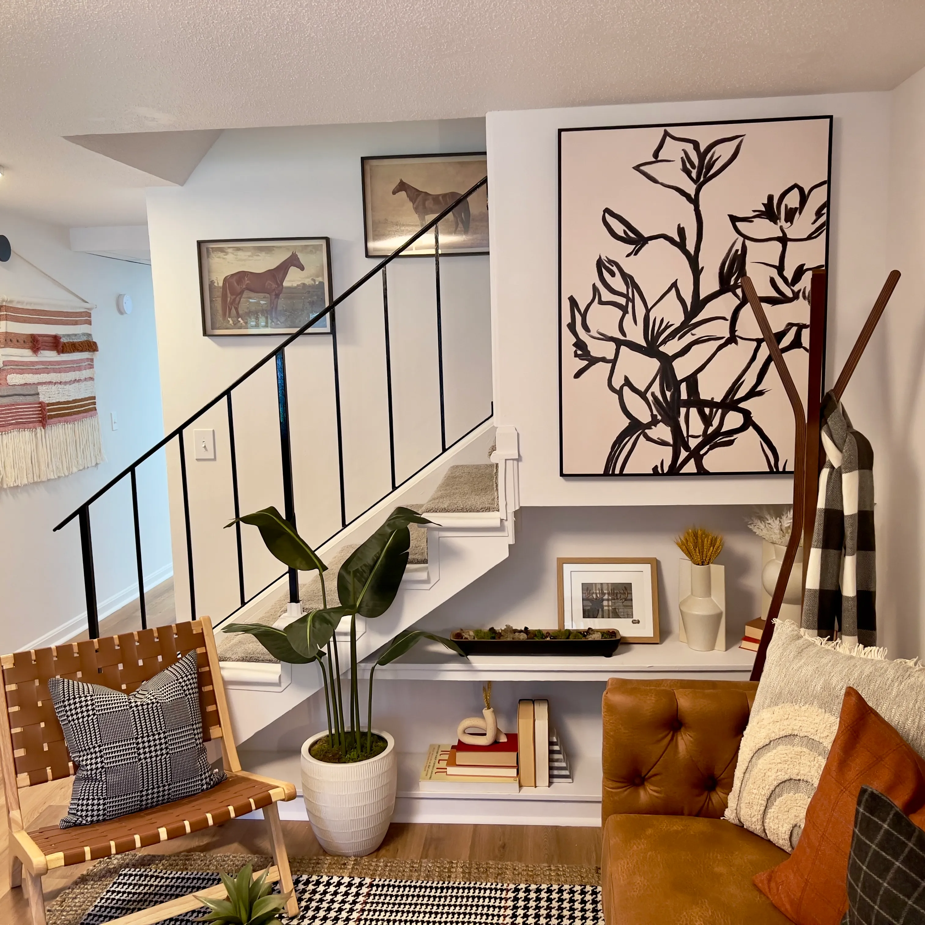 Dedicated workspace or study nook in a bedroom at The Den apartments in Willington, CT, featuring a dark wood desk, metal chair, and gallery wall art.