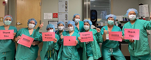 Nine medical workers in scrubs and masks holding signs thanking Iroquois and carrier partners for support during COVID.