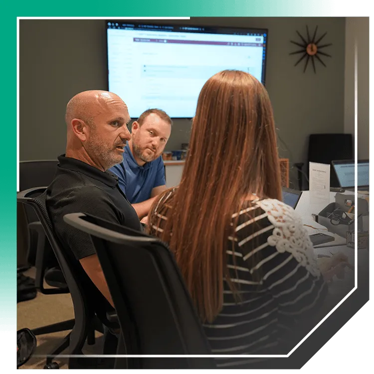 Office team meeting around laptops reviewing project plans on-screen to coordinate foundation repair estimates