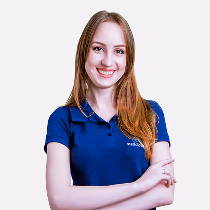 Mulher sorridente de cabelo longo loiro usando camisa polo azul com braços cruzados.