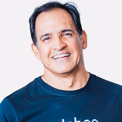 Homem sorridente com camiseta preta em fundo claro.