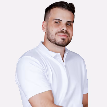 Homem com barba curta e cabelo escuro, vestindo camisa polo branca, posando com leve sorriso.
