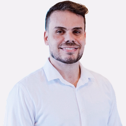 Homem com barba curta e cabelo escuro, vestindo camisa polo branca, posando com leve sorriso.
