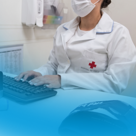 Profissional de saúde de jaleco branco com máscara digitando em teclado de computador.