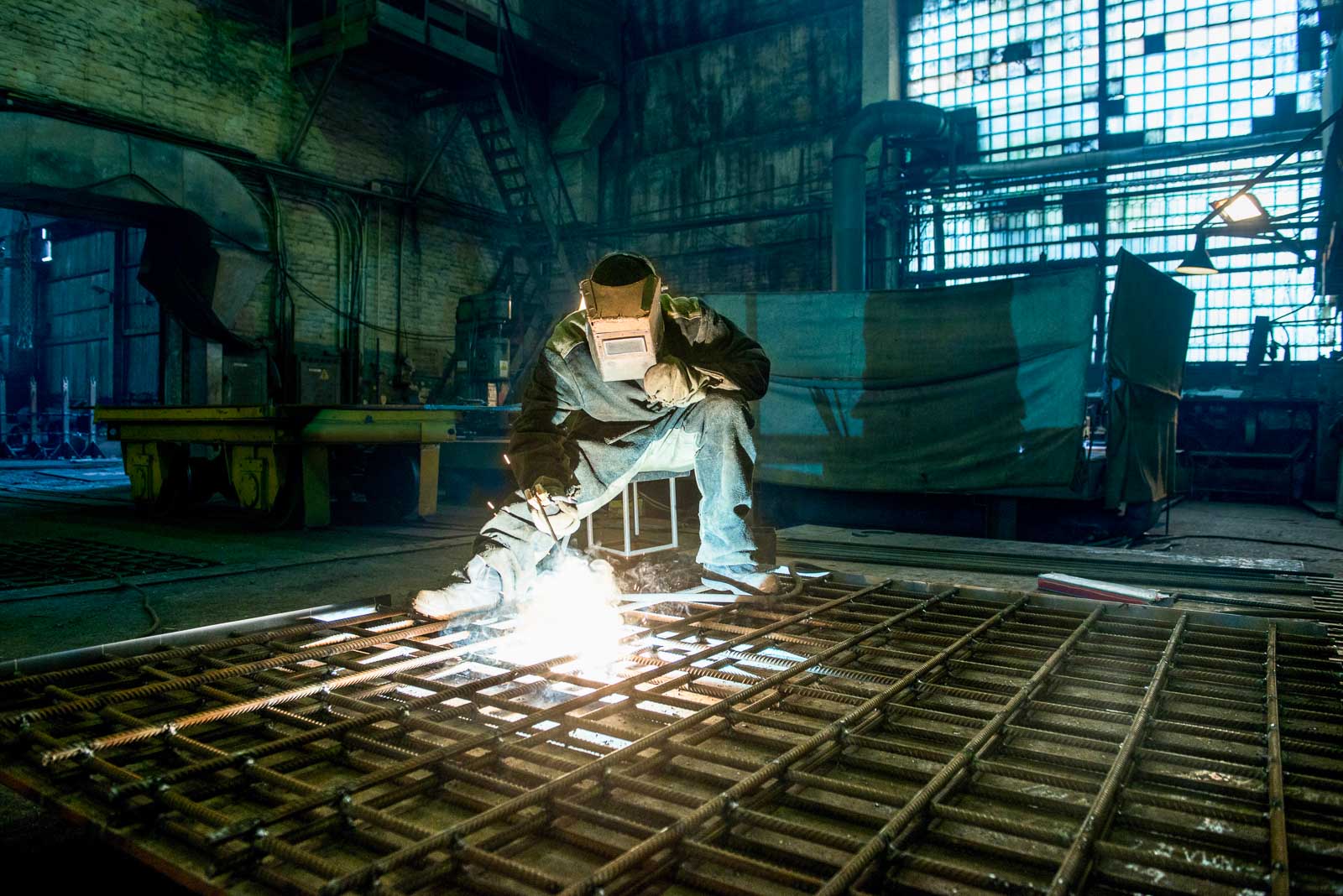 Welder joining steel framing in an industrial fabrication shop