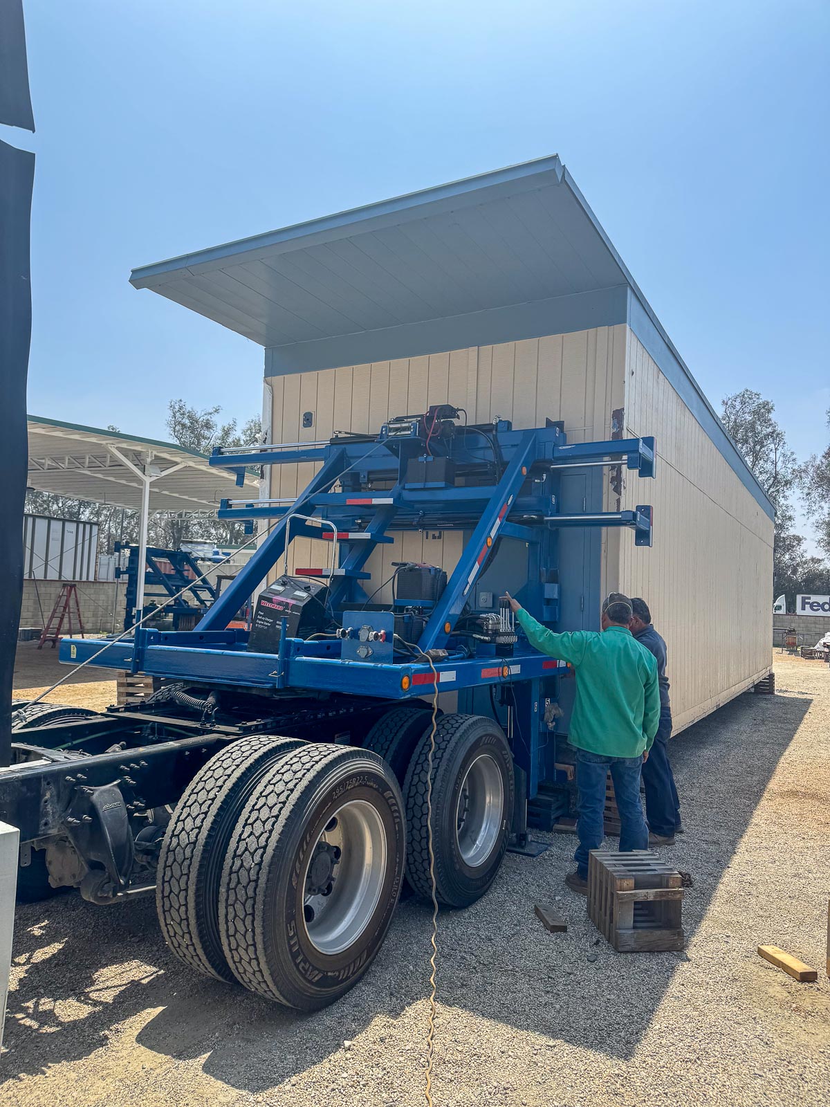 Crew moving a modular classroom with a hydraulic transporter