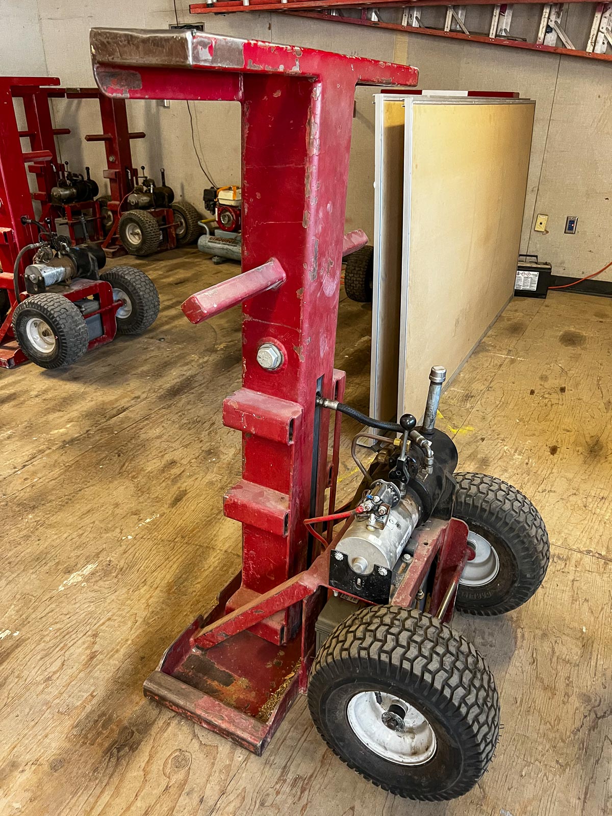 Side view of a red hydraulic jack on rubber tires