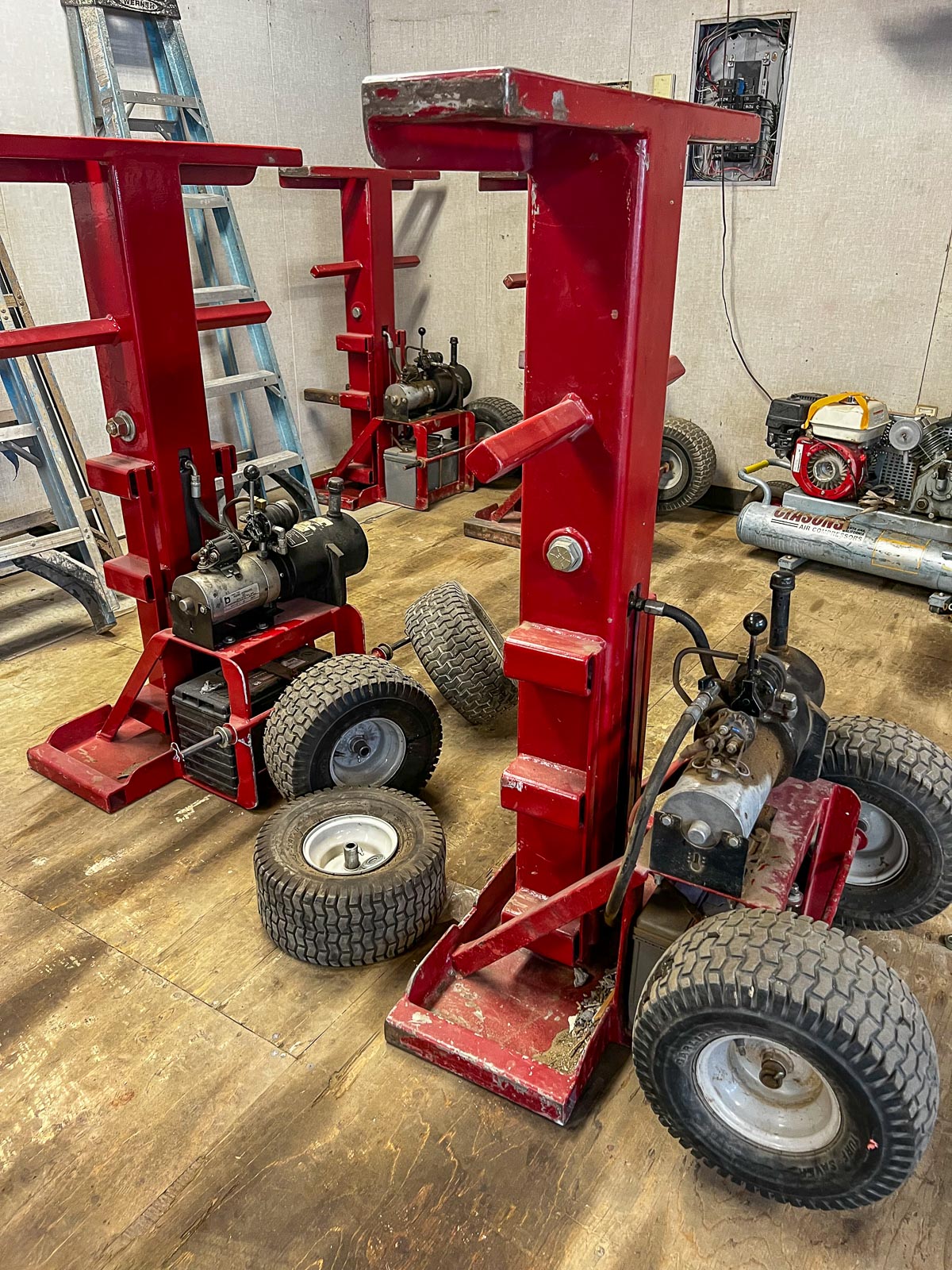 Pair of red hydraulic jacks staged in the fabrication shop