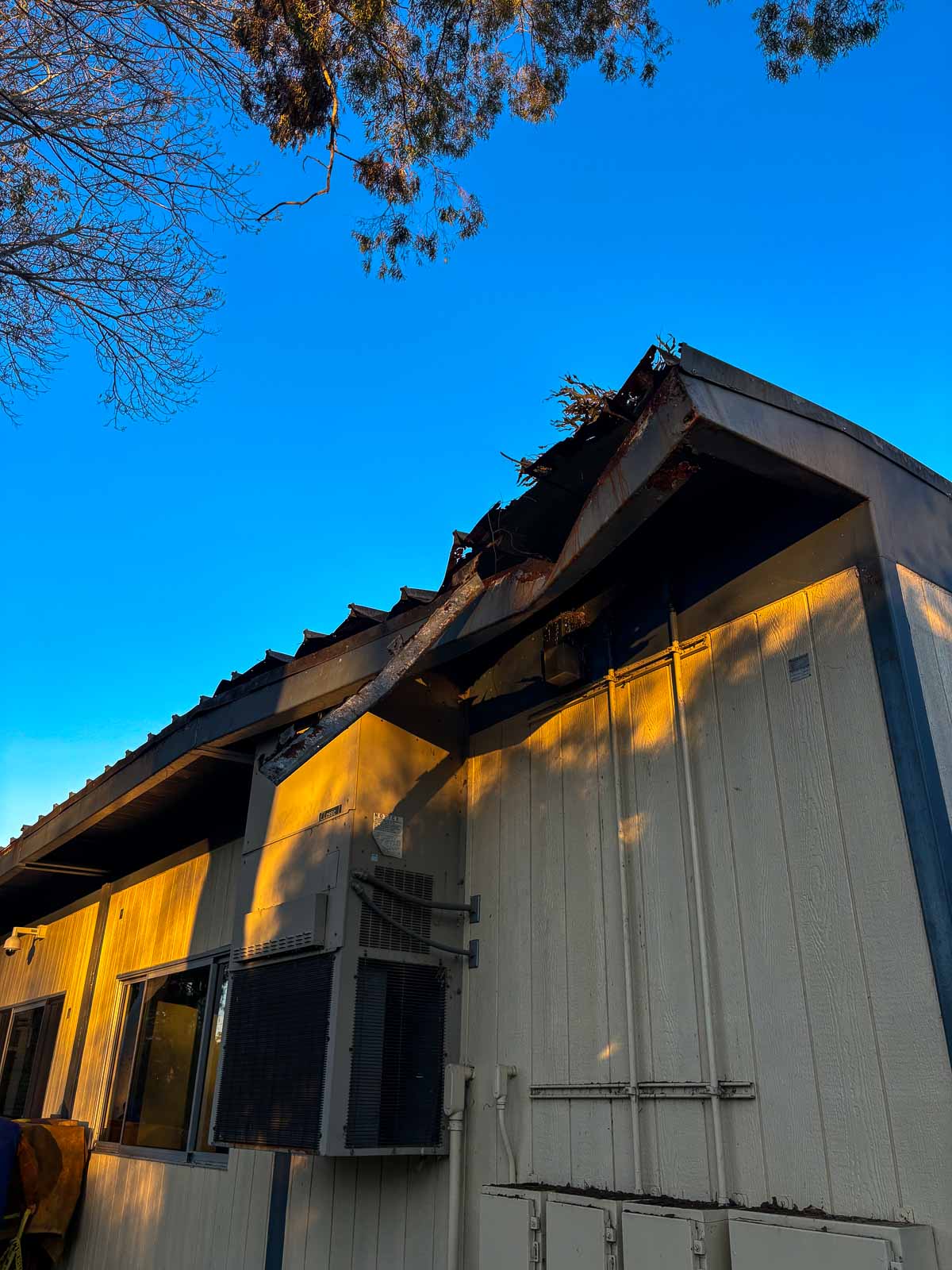 Before: deteriorated fascia and torn roof edge on a modular classroom