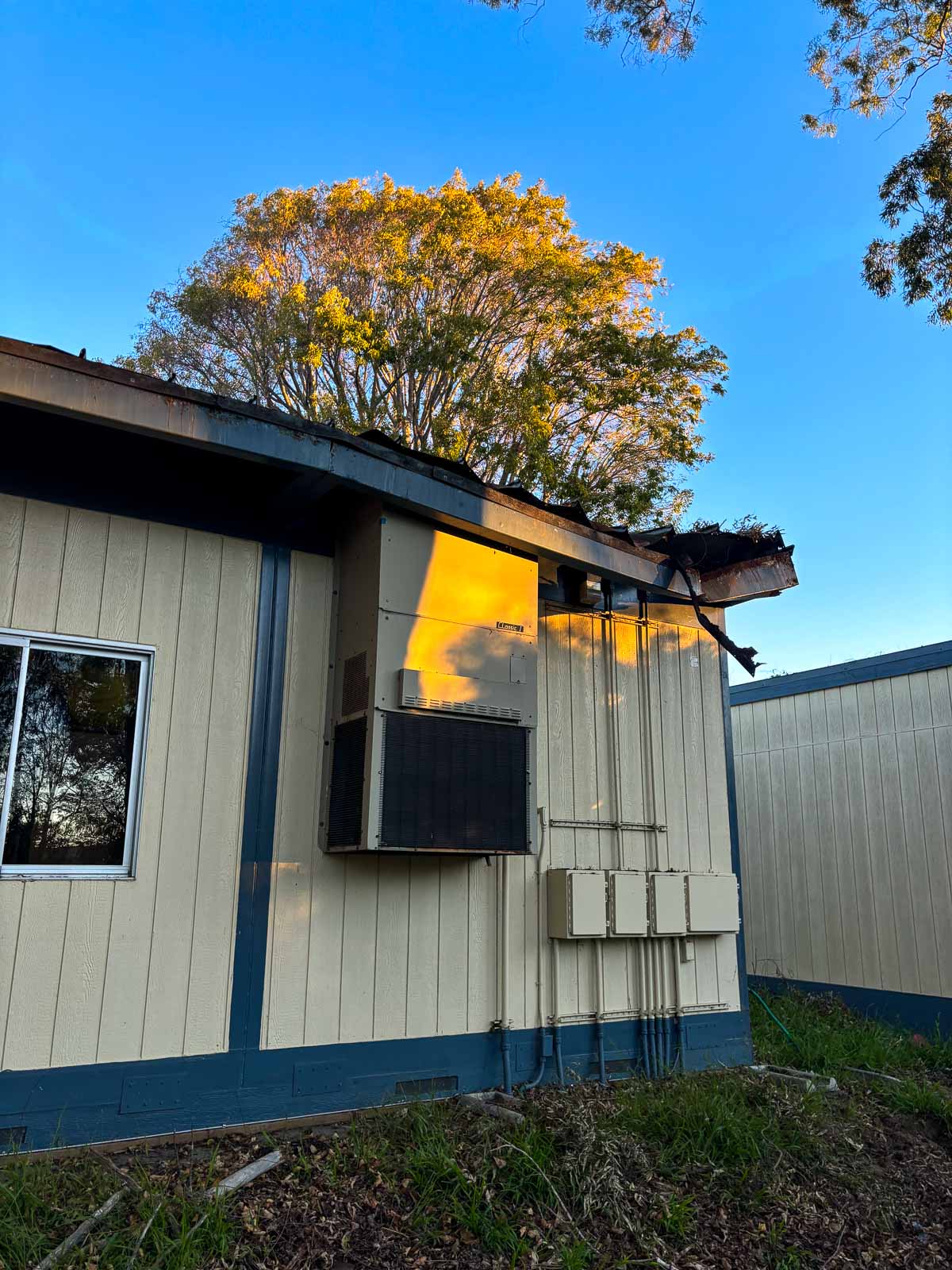 Before: damaged eave and worn siding on the classroom exterior