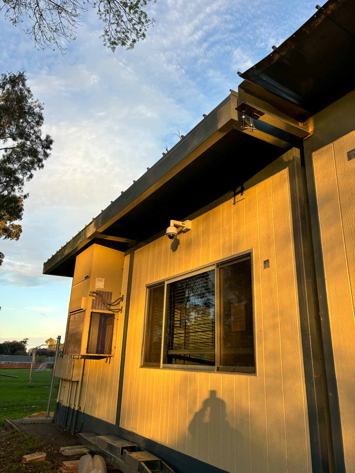 Before: weathered siding and damaged roof overhang on a modular classroom