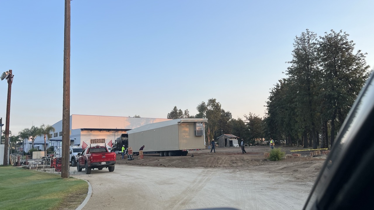 Modular classroom buildings and delivery trucks staged at the school site