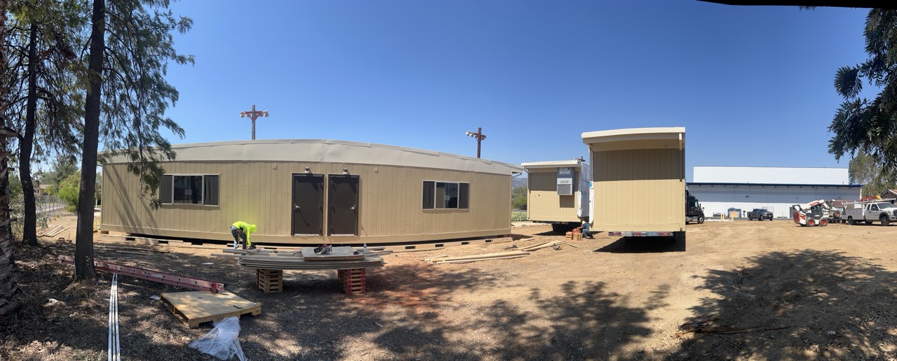 Crew leveling a modular classroom unit on its foundation