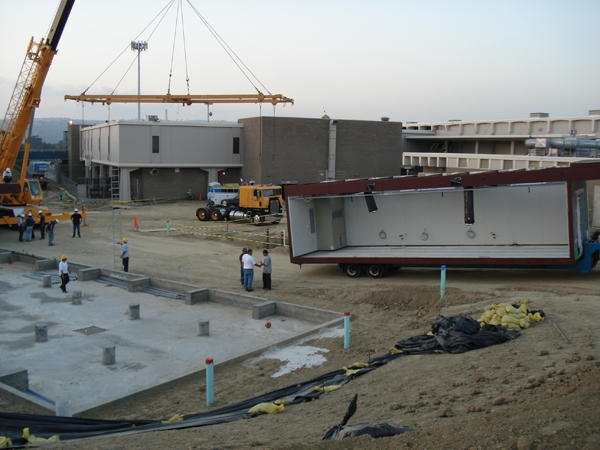 Crane placing a modular restroom module at the school