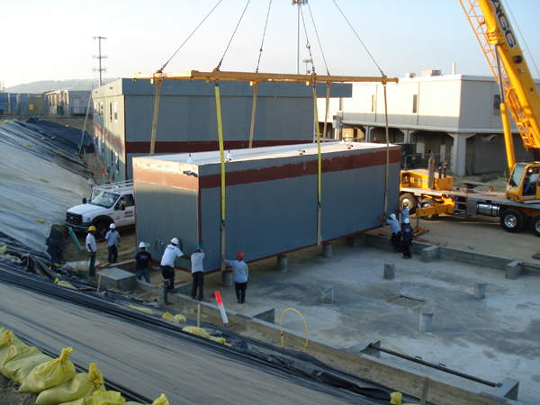Crew guiding a modular module into position with the crane