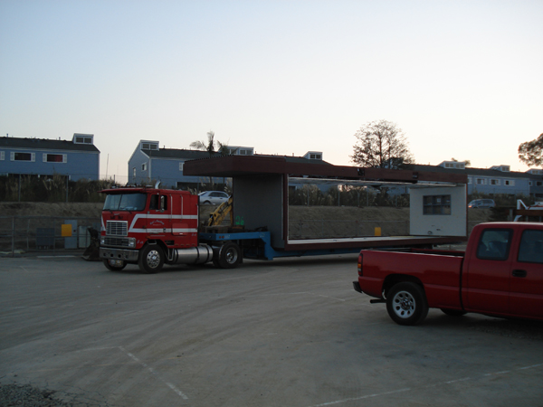Trucks and trailer delivering modular units at dusk
