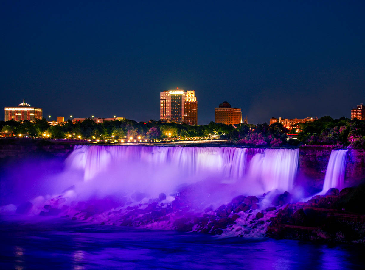 Niagara Falls from the Canadian side showing the American Falls in bright purple. The waterfall is purple because of the colorful lightshow that takes place every night at the falls.