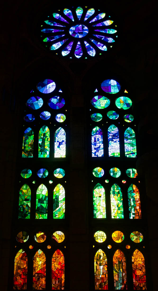 A stained glass window inside the famous Sagrada Família cathedral in Barcelona, Spain. This window is an ombre colored window which changes from blue at the top, green in the middle, and yellow, orange and red at the bottom.