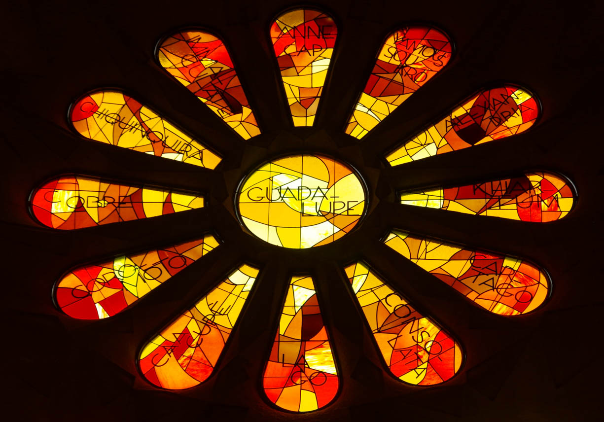 A red and orange stain glass window in the shape of a flower with petals in the Sagrada Família cathedral in Barcelona, Spain.  