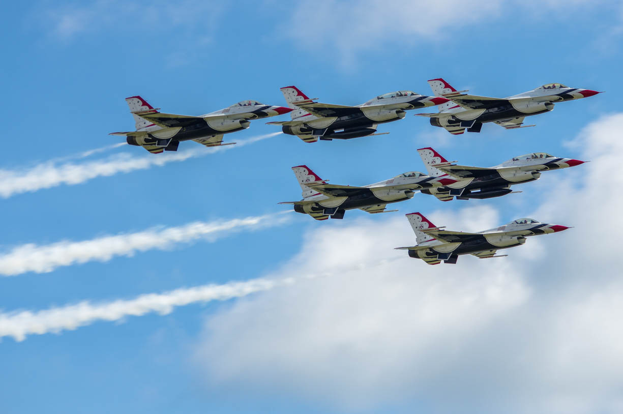 USAF Air Force Thunderbirds photographed at the Grissom Air Force Base during the Grissom Airshow in central Indiana, USA in 2019. The group of six planes are flying in tight formation in the top right of the image. The planes are red, blue, and white with their smoke trails on.