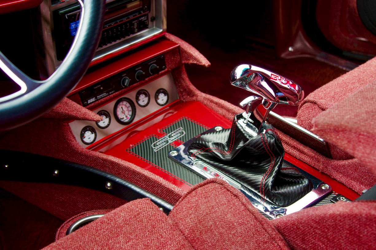 This image shows the gearshift and spectacular interior of the El Meano (a customized El Camino) in Northern Indiana during the summer of 2021. The interior of the car is predominantly red. The El Camino is also an El Camino SS.