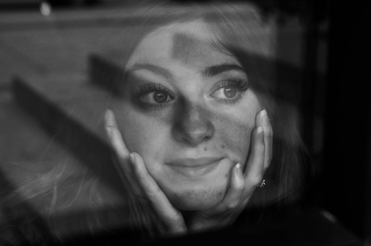 Face of a girl captured through a window with a shadow of stairs. 