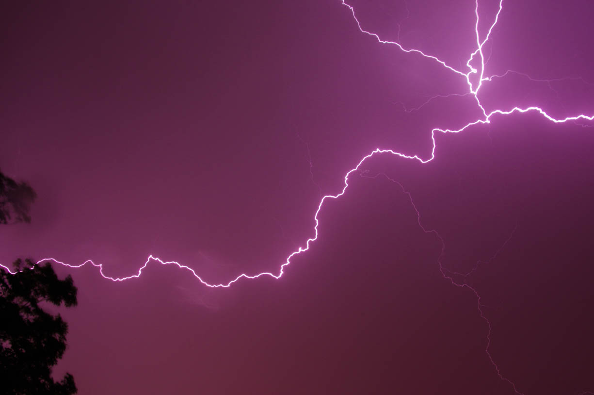 This image shows a vibrant lighting strike in a cloudy purple sky 