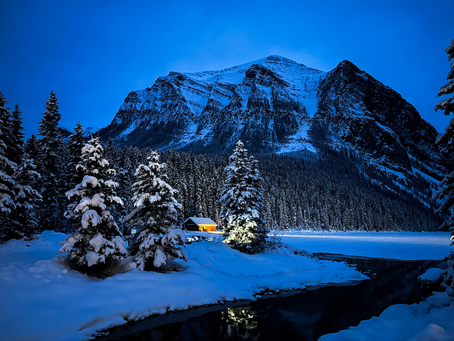 A scenic image of a mountain, a small shed, and pine trees in Banff, Alberta, Canada, in the Canadian Rockies