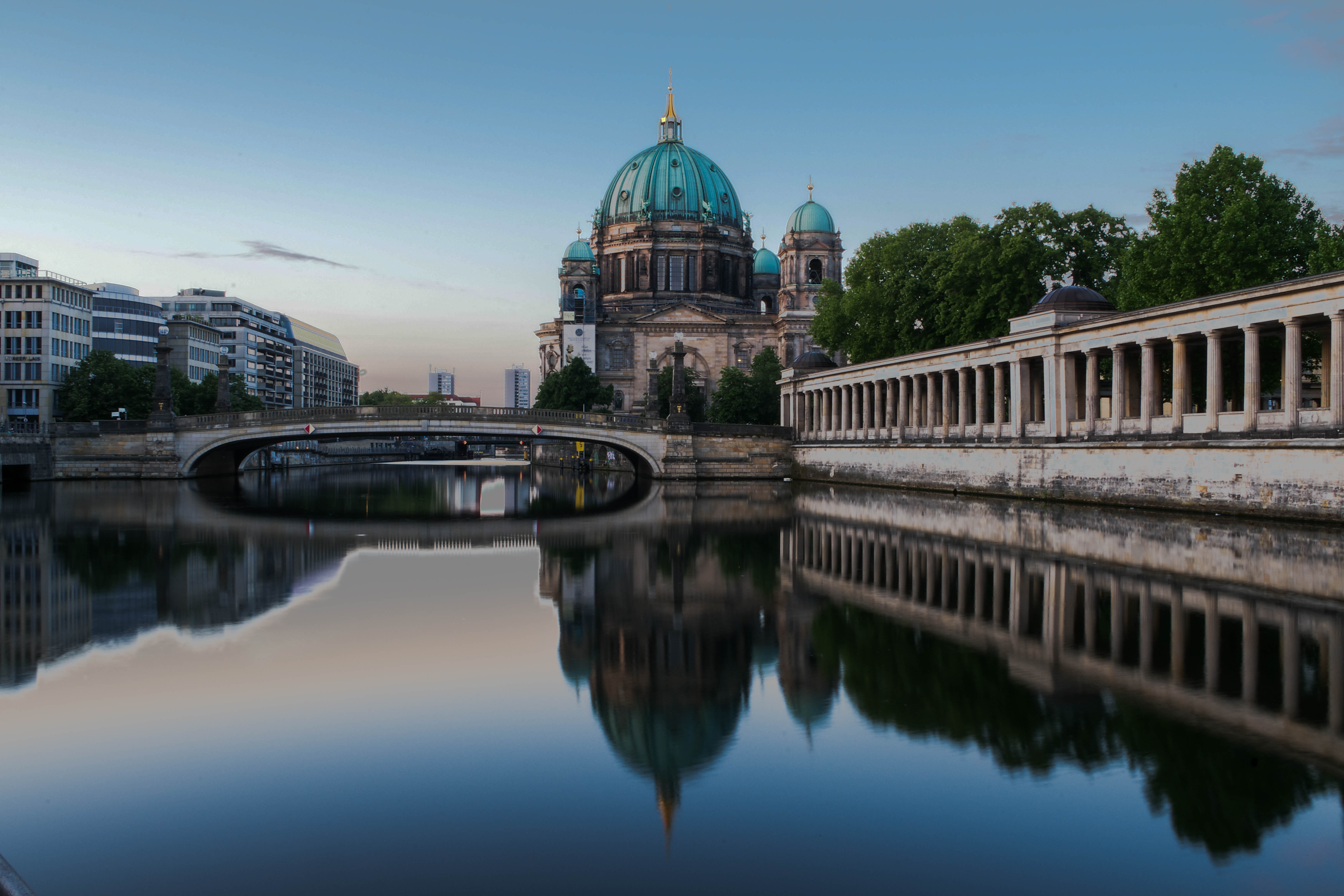 The spectacular stain glass window ceiling in the Palau de la Música Catalana in Barcelona, Spain. The stain glass window is red and orange in the middle like the sun, with blue, purple, and green surrounding it in a circular shape. Also around the sun-like shape are countless stain glass women with floral crowns. Both sides are symmetrical.
