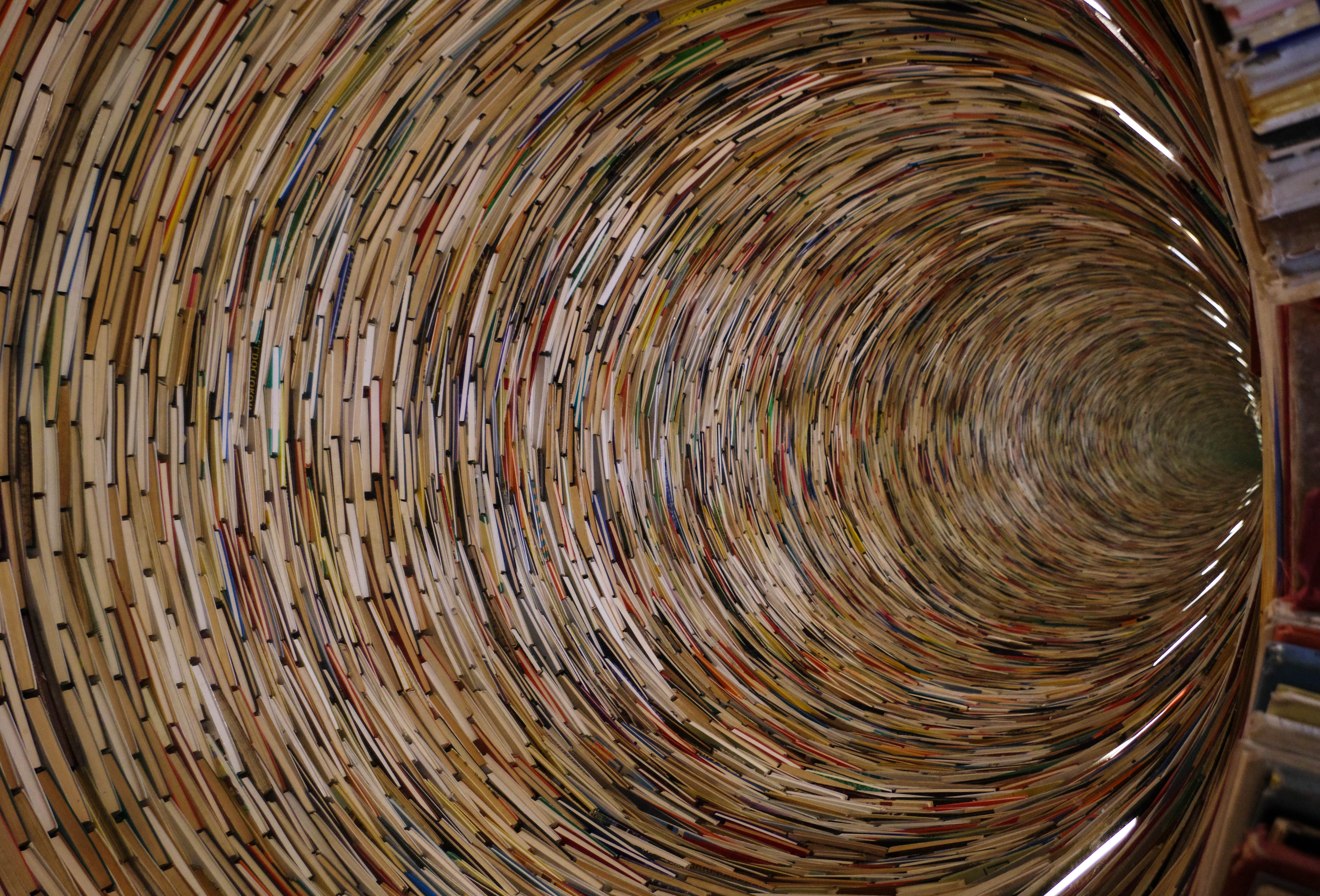 The spectacular stain glass window ceiling in the Palau de la Música Catalana in Barcelona, Spain. The stain glass window is red and orange in the middle like the sun, with blue, purple, and green surrounding it in a circular shape. Also around the sun-like shape are countless stain glass women with floral crowns. Both sides are symmetrical.
