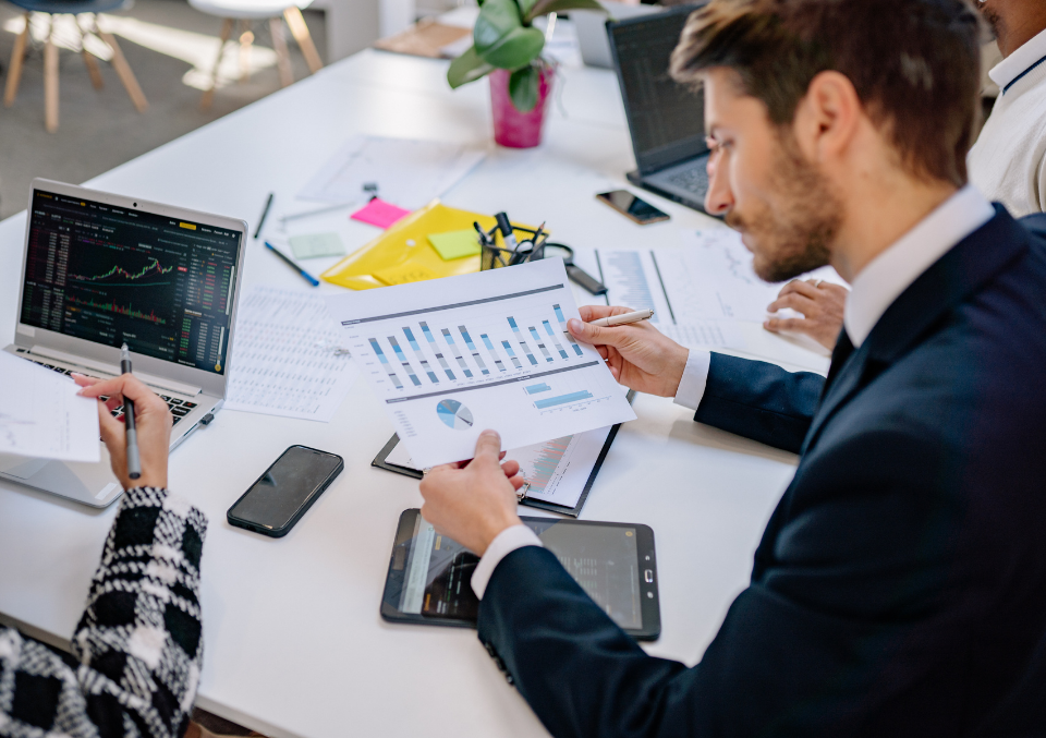Business team collaborating on a financial report, analyzing data visualizations and charts during a boardroom strategy meeting.