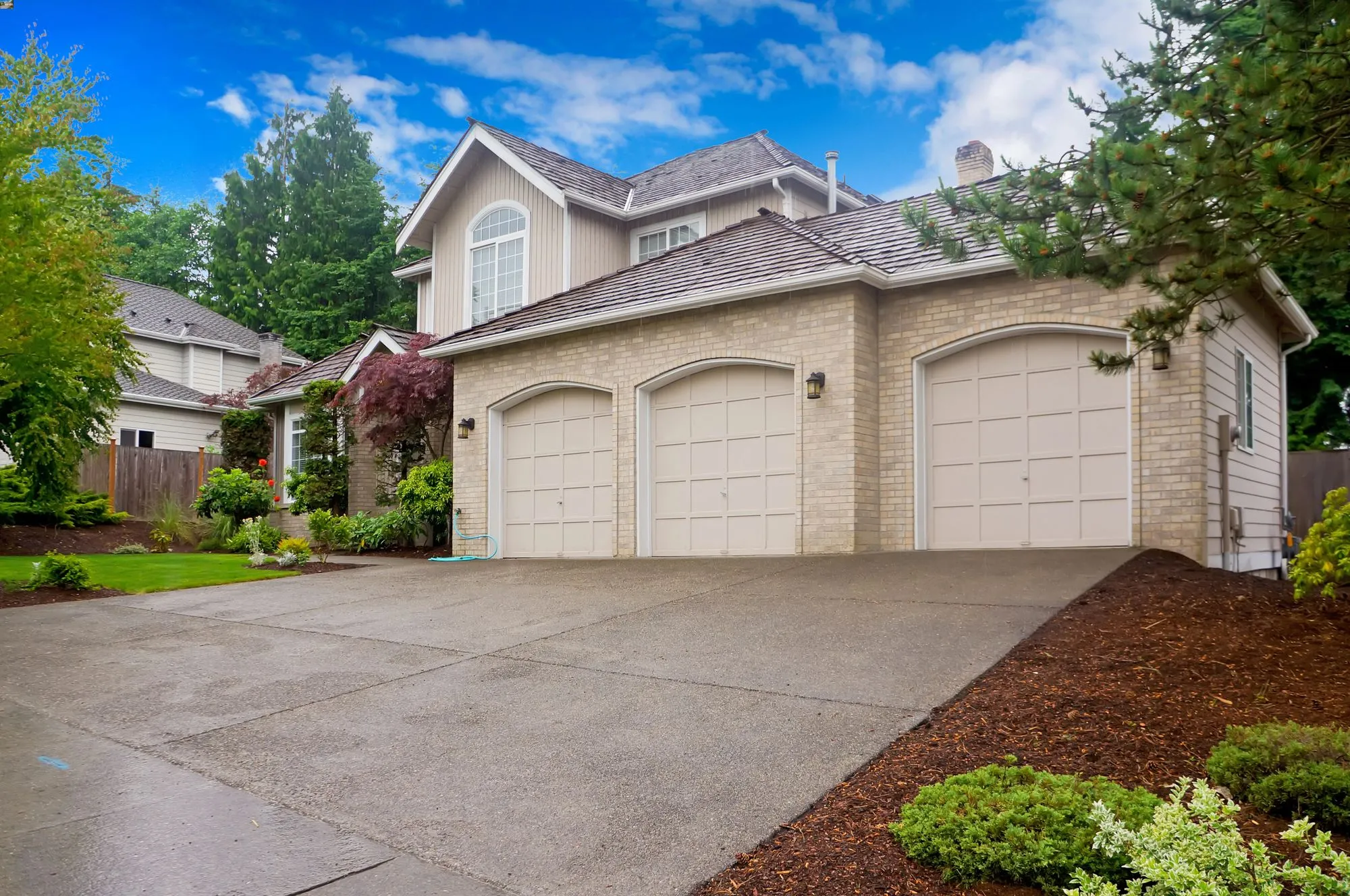 A pristine black asphalt driveway, providing a clear path to the entrance of a home, surrounded by greenery.