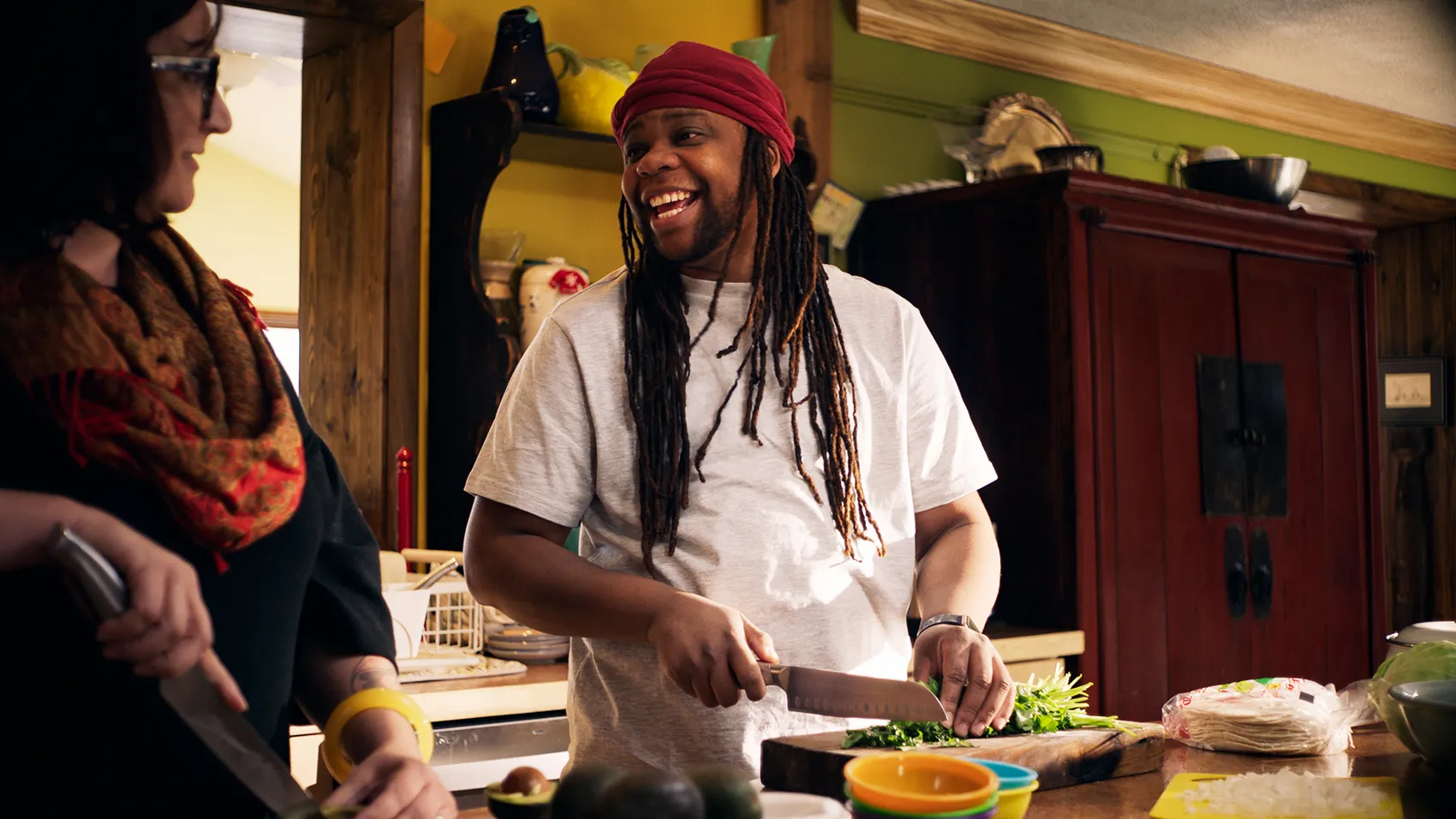 Gio preparing food, grinning to another person