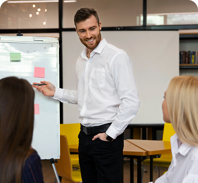 A person happily presenting to the team on a whiteboard in a conference room