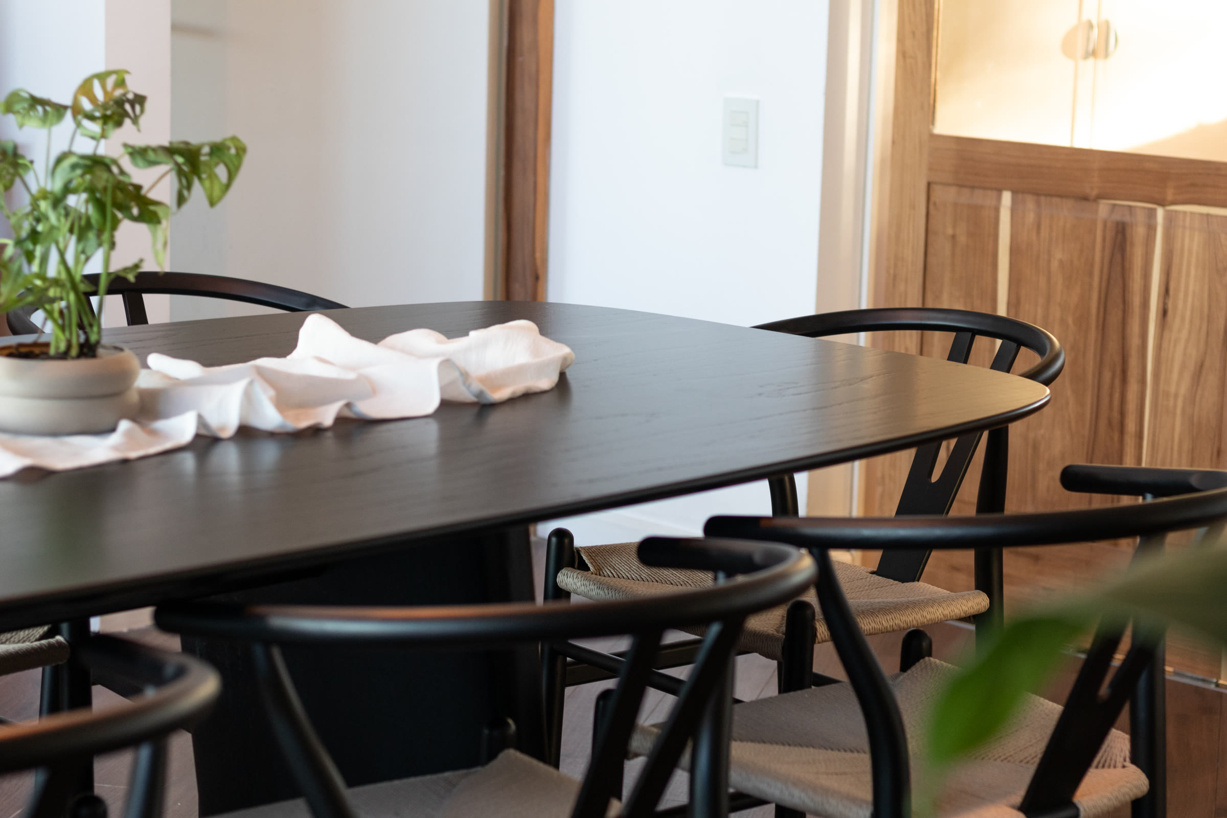Black dining table with wishbone-style chairs in a bright dining room