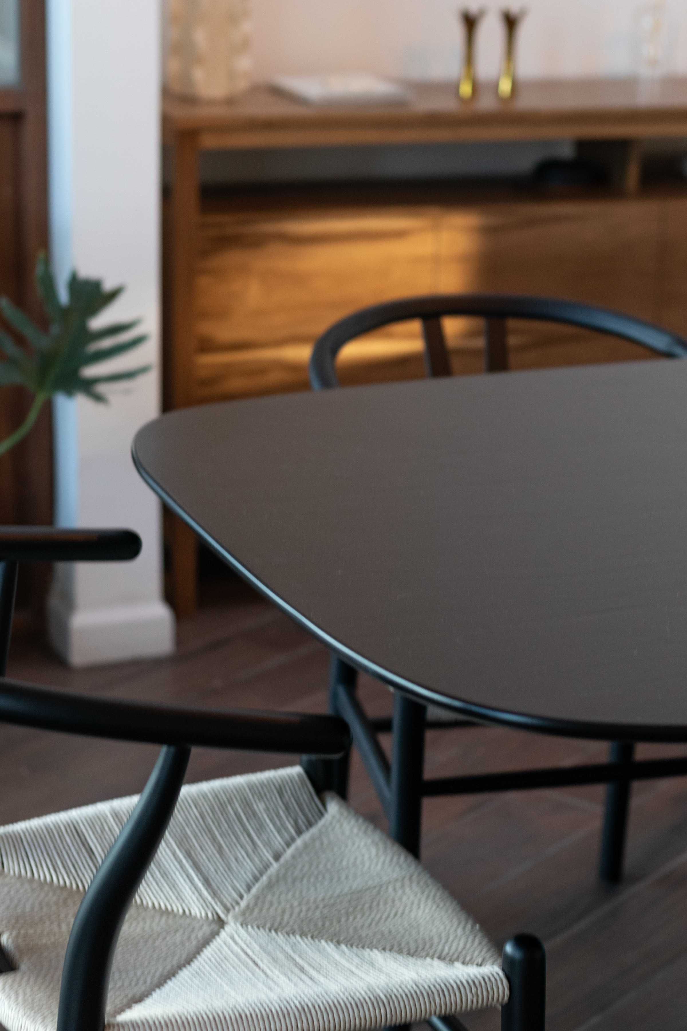 Dark wood dining table corner with woven-seat chair and oak sideboard