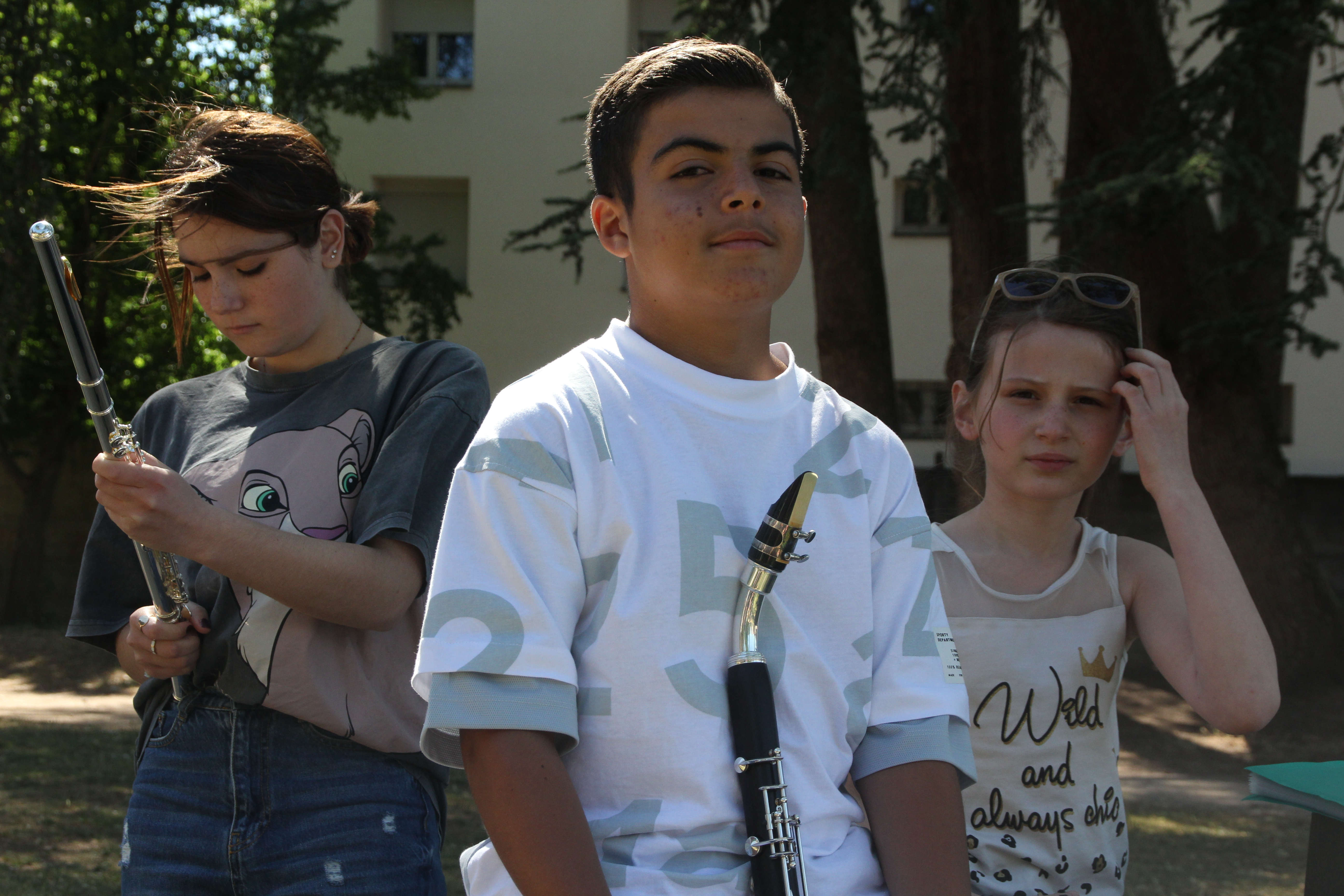 Trois élèves prenant la pose avec leur instrument en main face caméra