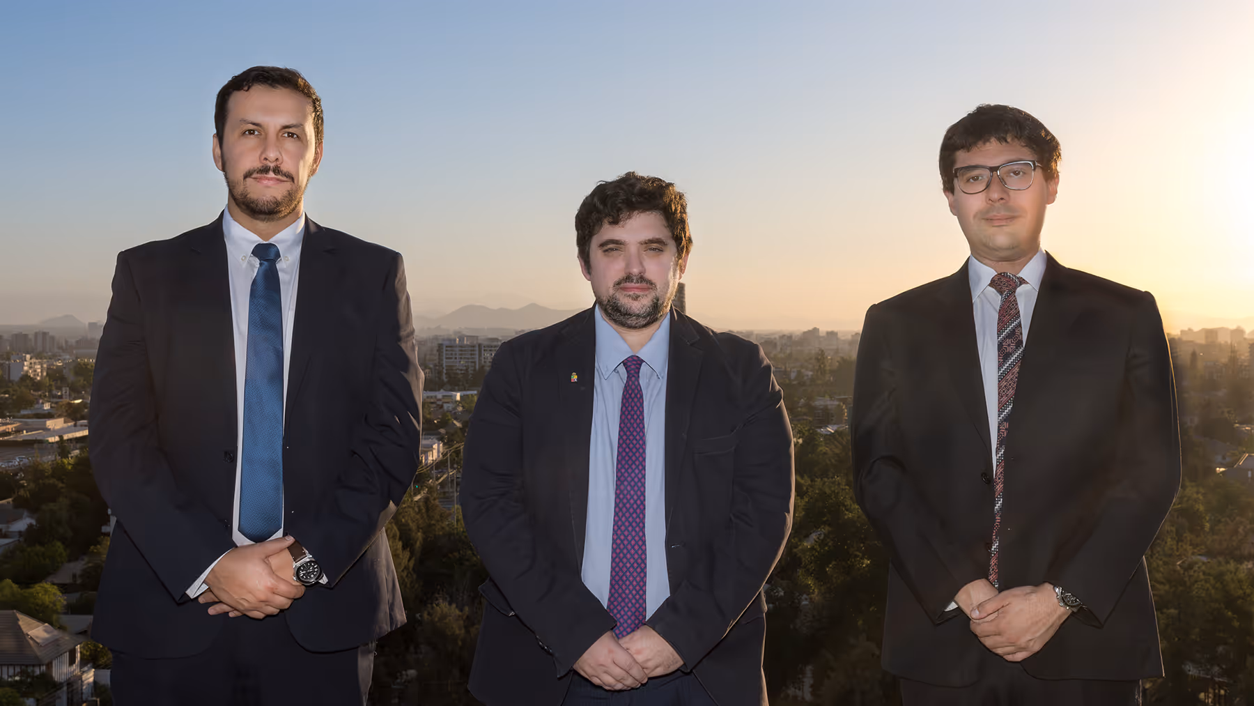 A picture of three men in suits, with a city on the background