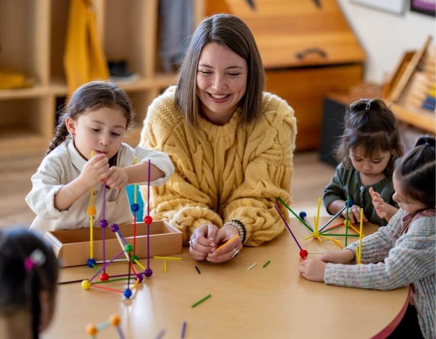 Pädagogische Fachkraft arbeitet mit Kindern an einem Bastelprojekt – Beispiel für eine praxisnahe Tätigkeit im Rahmen eines dualen Studiums Lehramt oder Kindheitspädagogik.